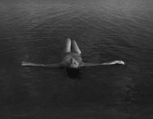 Akt kobiecy - kobieta pływa w jeziorze nago