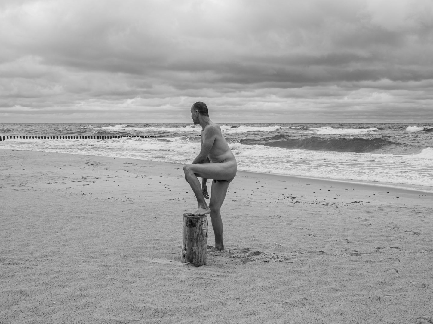 fotografia sensualna - mężczyzna pozujący nago na plaży nudystów